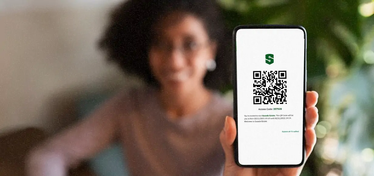 A person holding up a smartphone displaying a QR code for visitor access approval, emphasizing Sylogate's seamless visitor management system.